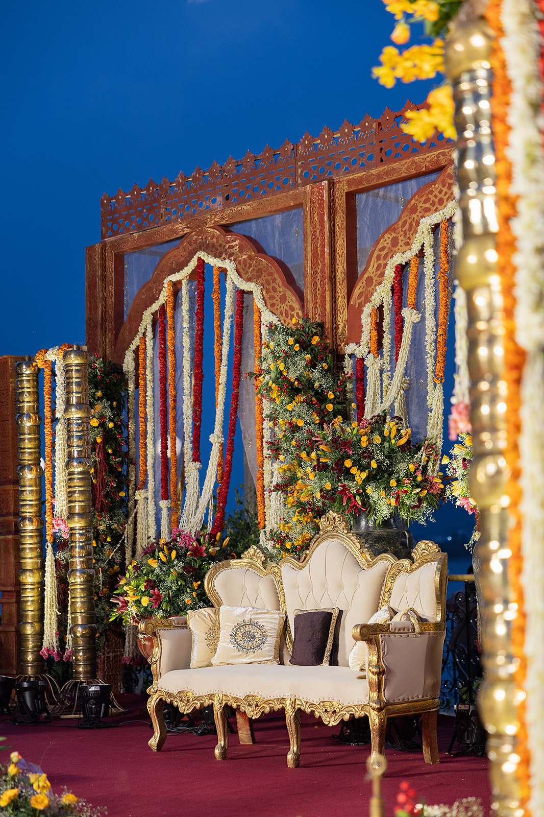 A floral stage set with garlands, gold pillars and a gilded sofa